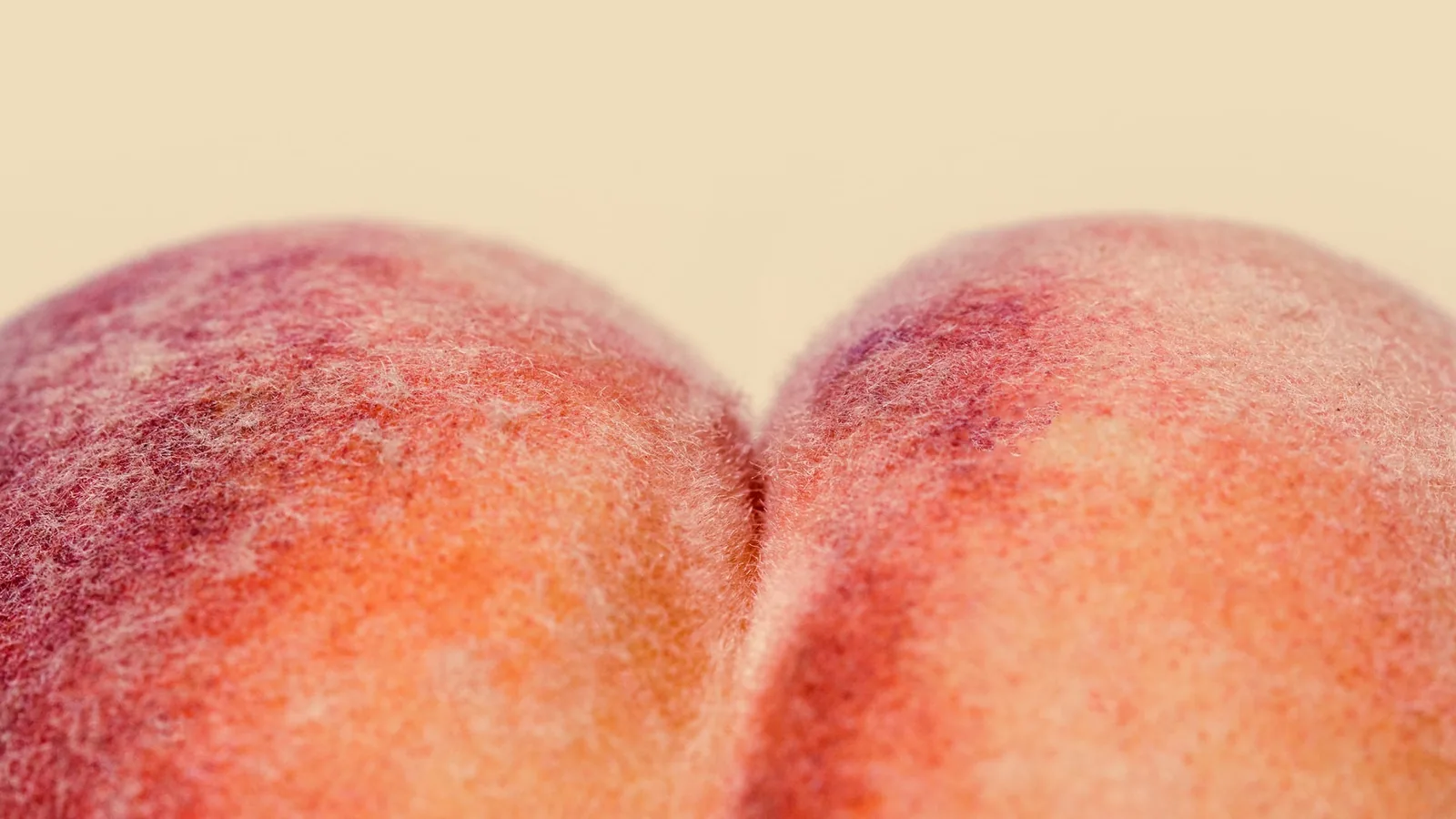Close-up of a ripe peach against a soft cream background