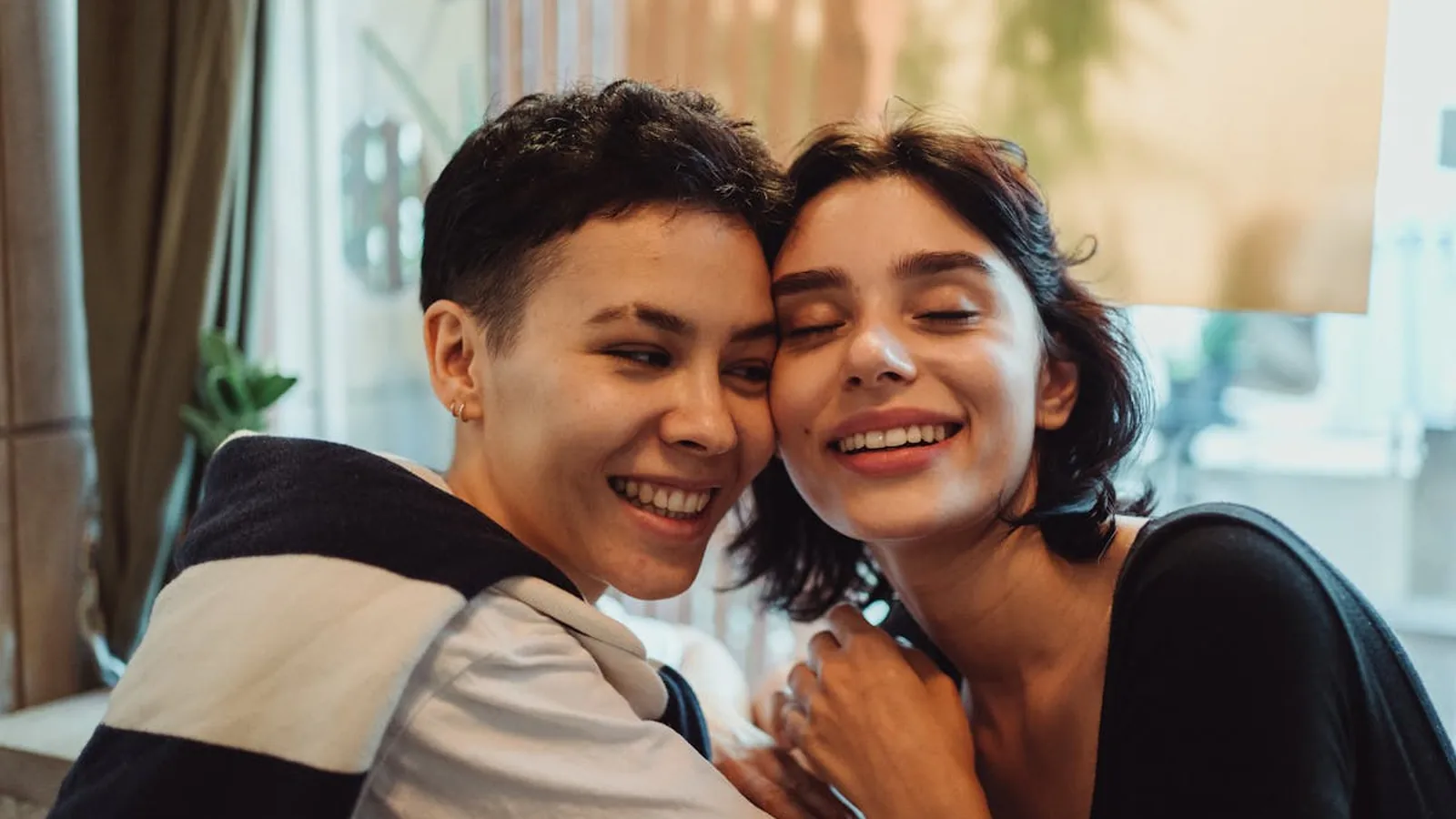 Two young women hugging and smiling with their cheeks pressed together