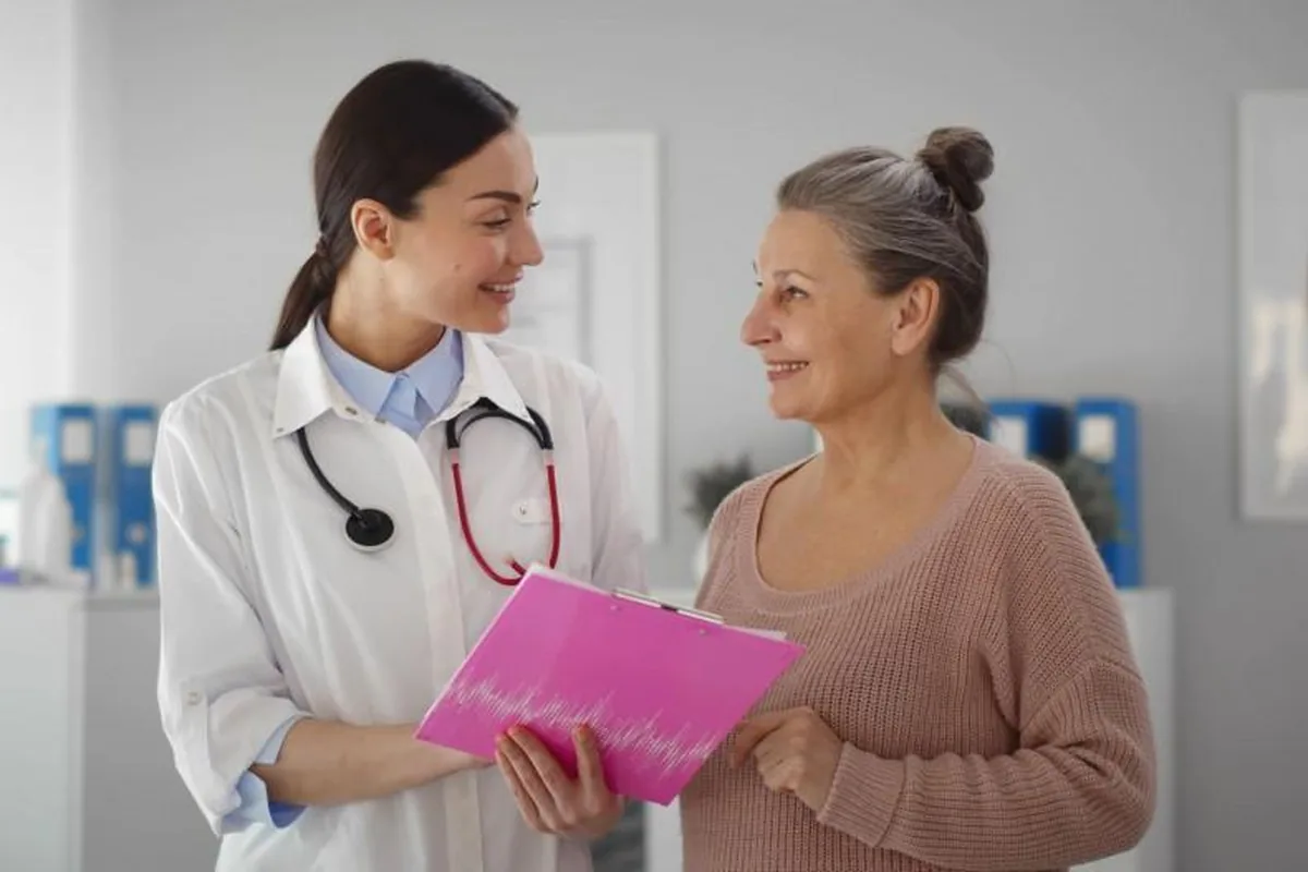 A doctor going over a pink folder with an older woman