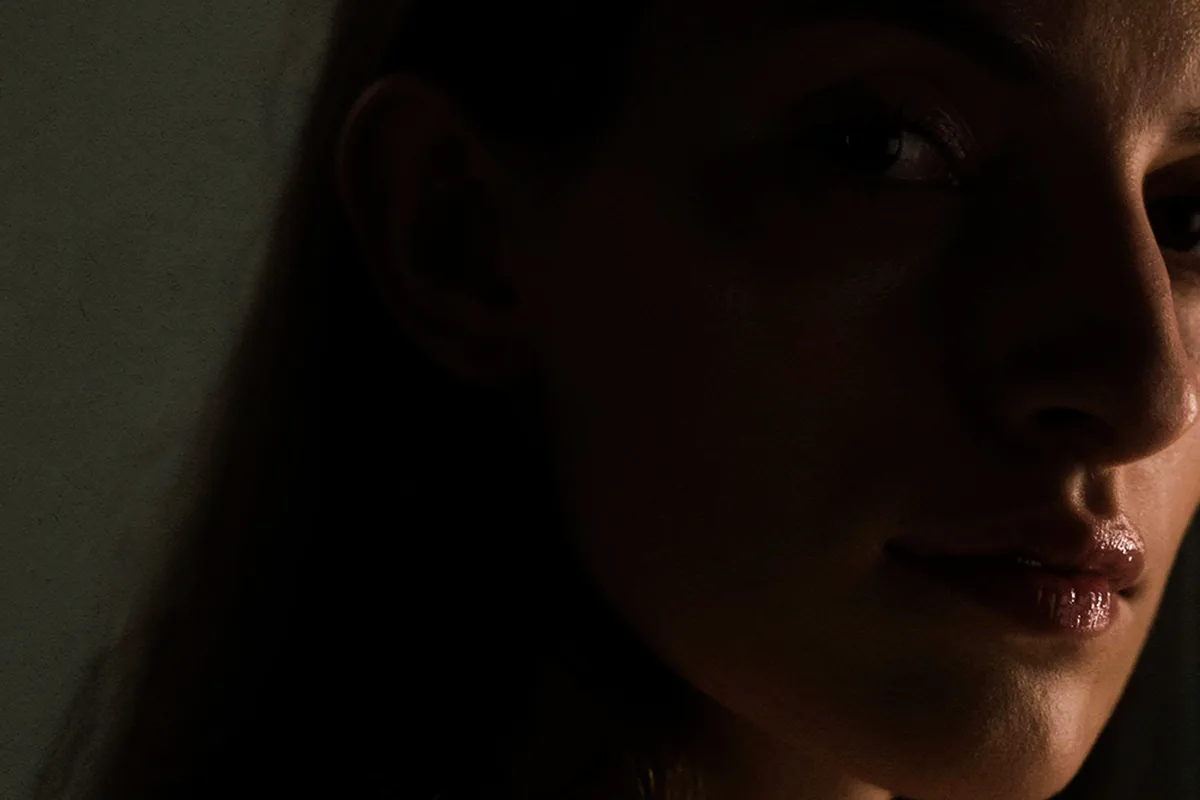 A woman’s face half in shadow, looking thoughtful
