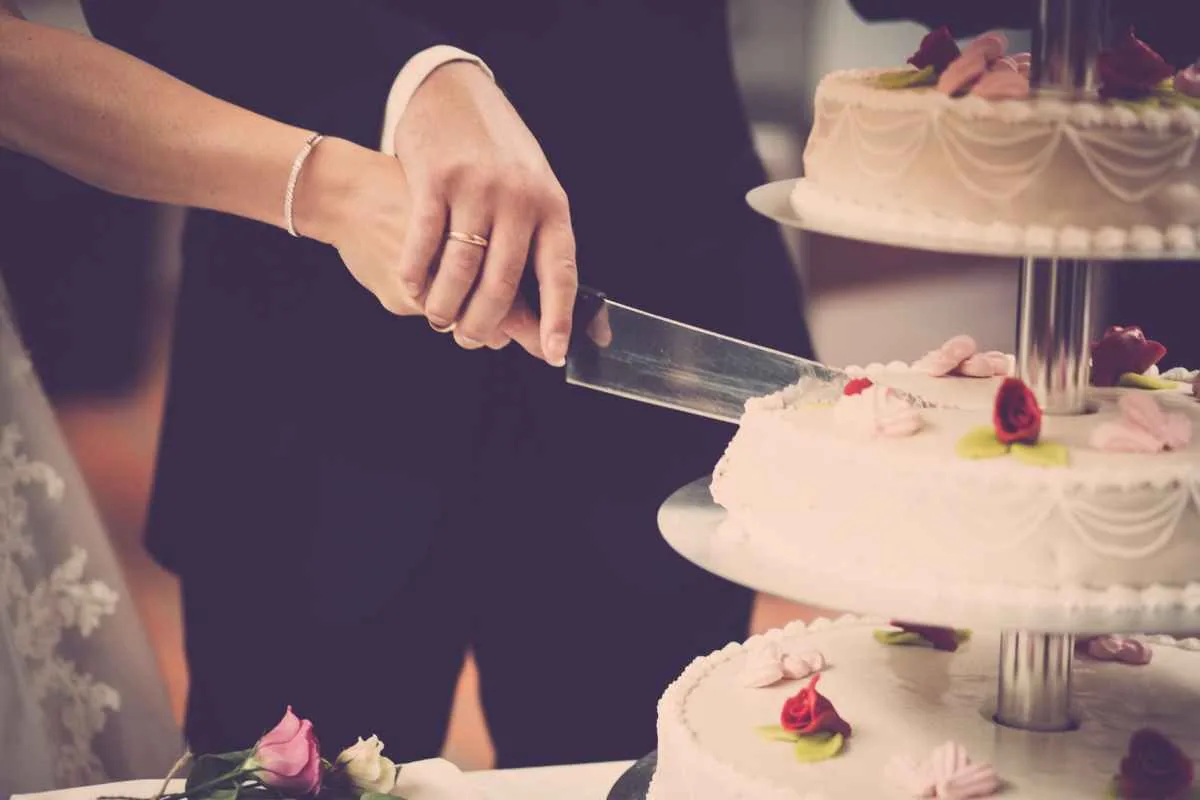 A couple cutting a tiered wedding cake together