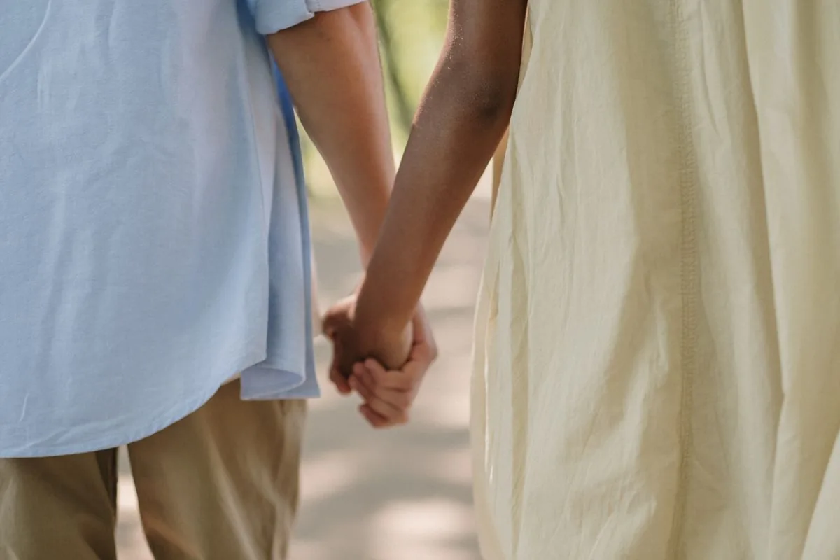 Two people walking hand in hand, seen from the waist down