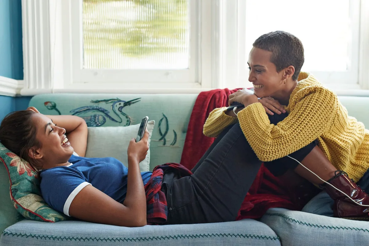 Two women relaxing and chatting on a sofa by a window