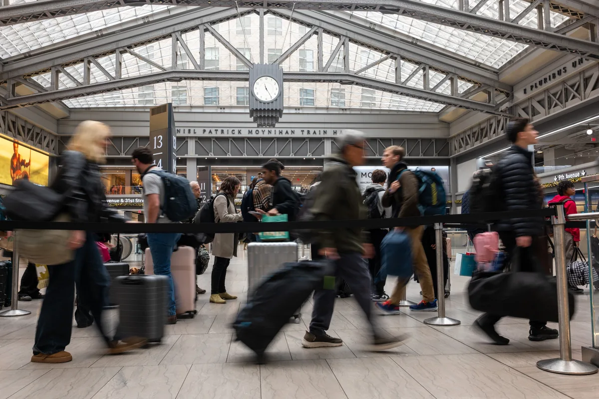 Crowds of travellers moving through a busy train station concourse