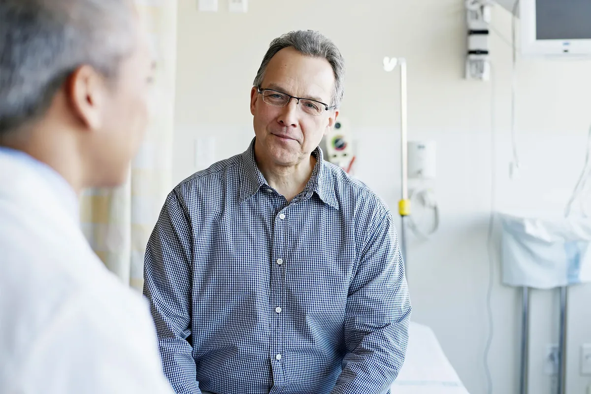 A middle-aged man talking with his doctor in a clinic room