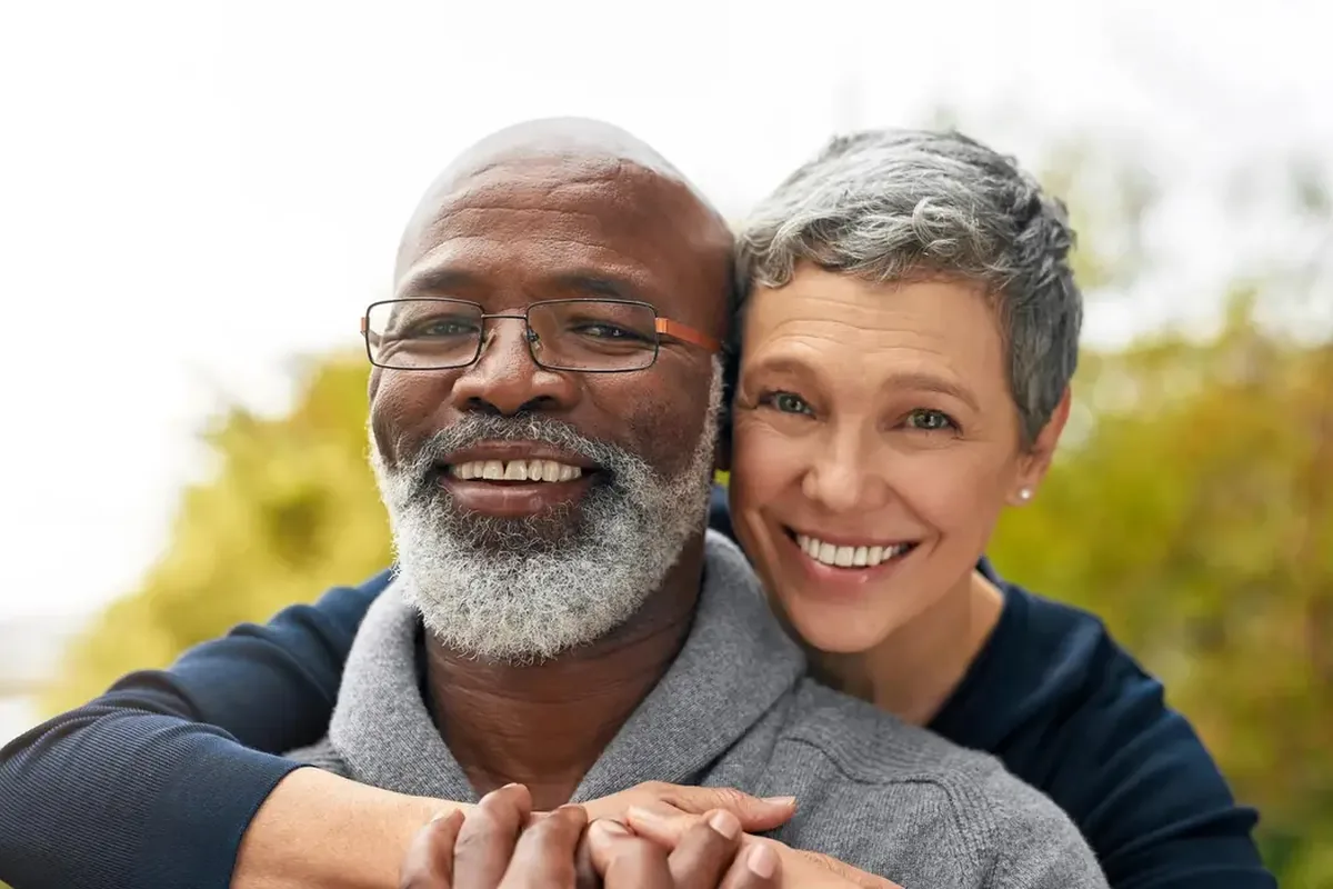 An older couple hugging and smiling outdoors