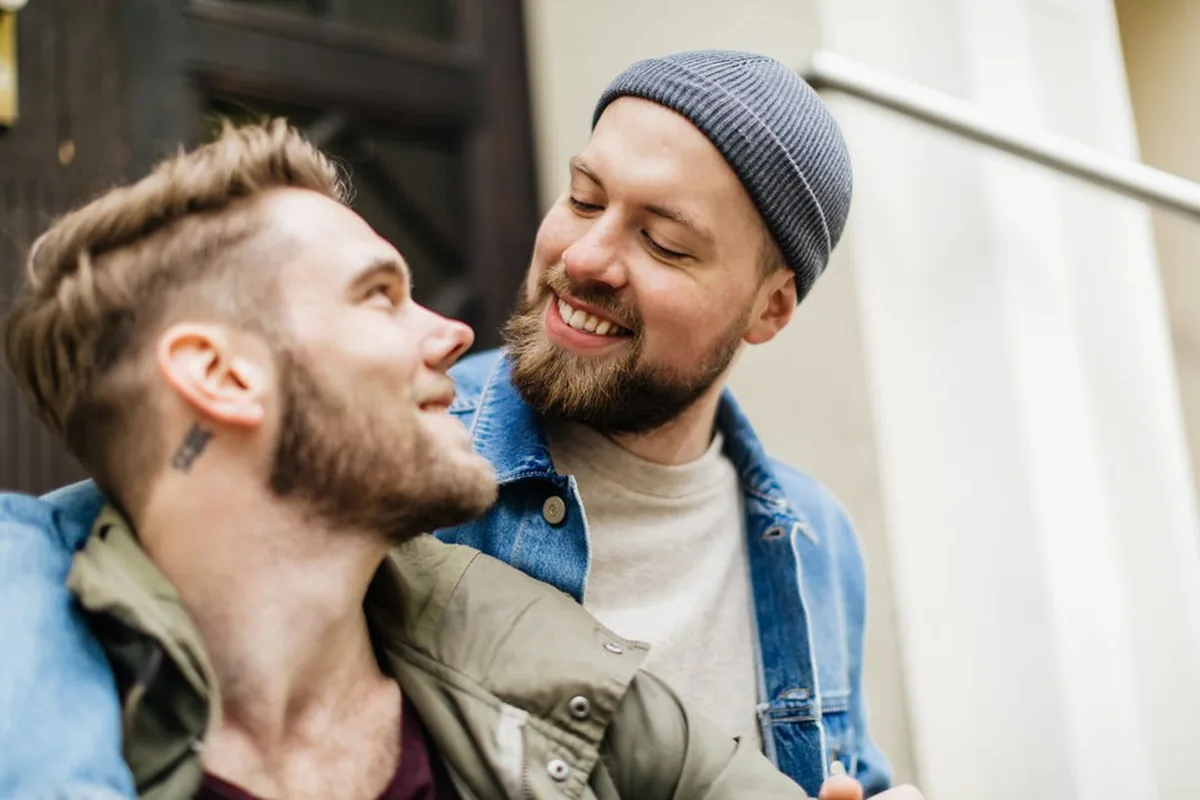 Two men smiling at each other on a city street