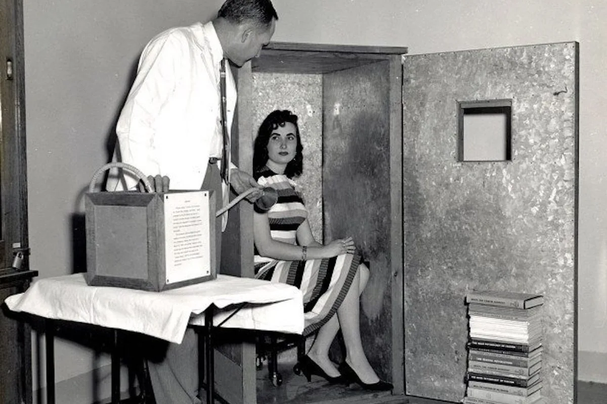 A vintage black-and-white photo of a 1950s research room with a woman seated in a booth