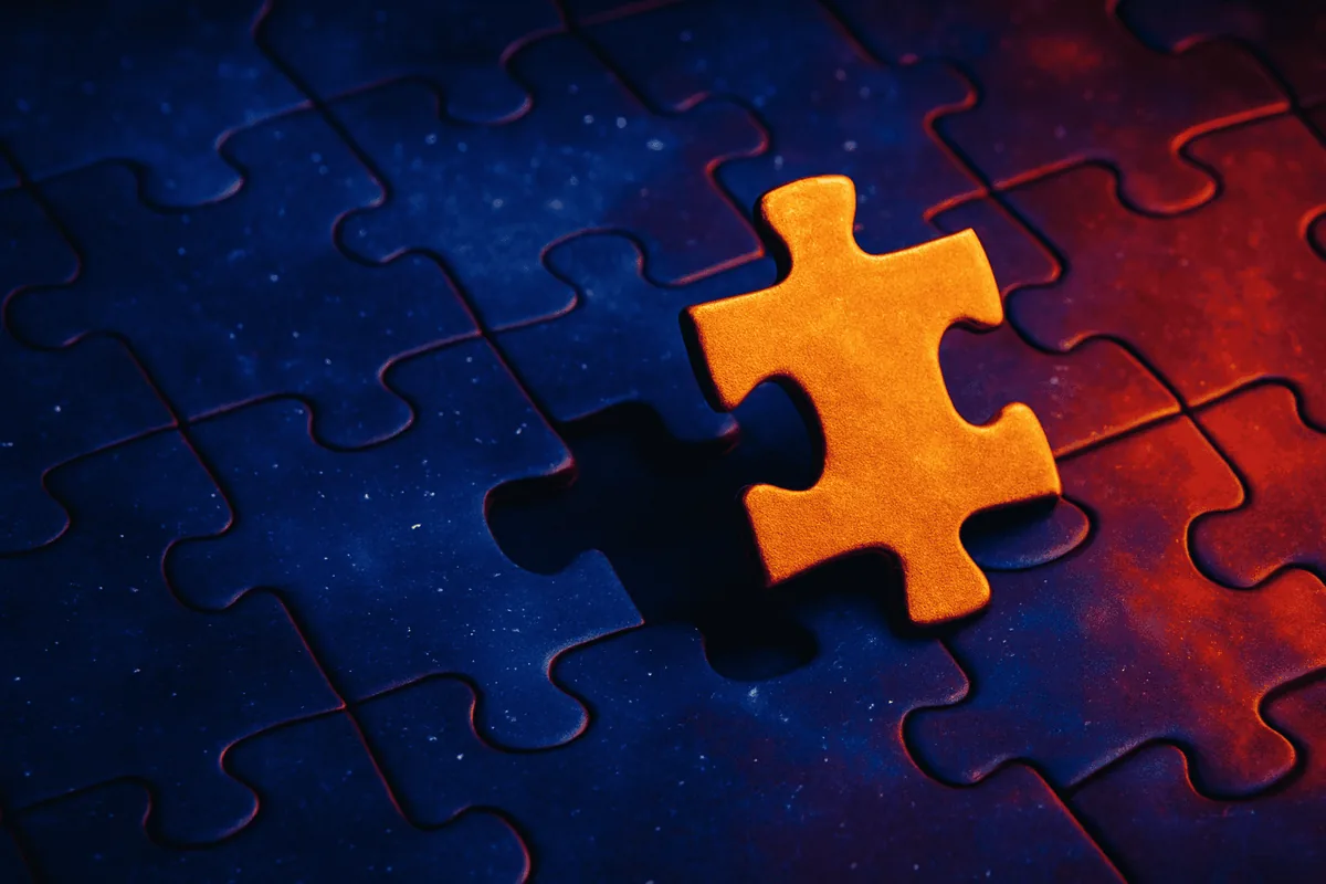 A single orange jigsaw piece lifted out of a dark blue puzzle