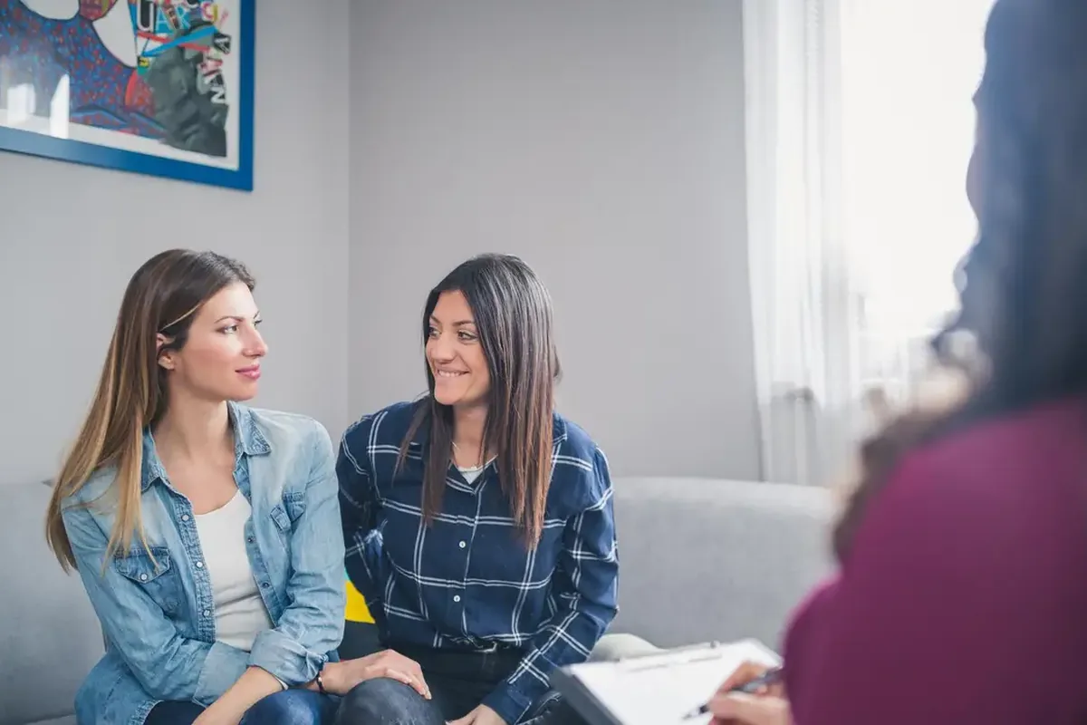 Two women on a sofa talking with a therapist