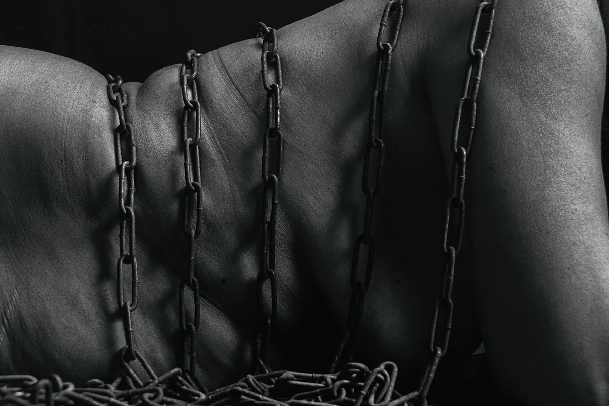 Black-and-white close-up of chains resting across a person’s bare back
