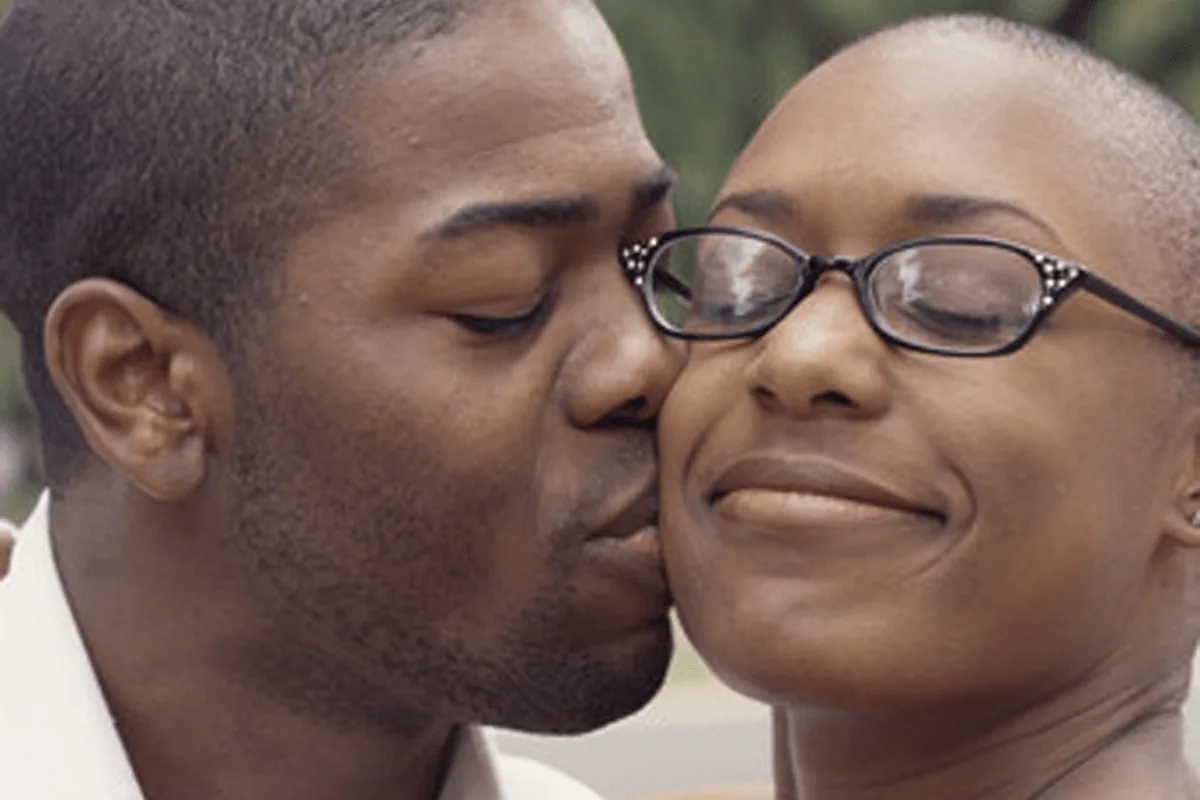 A man kissing a smiling woman on the cheek