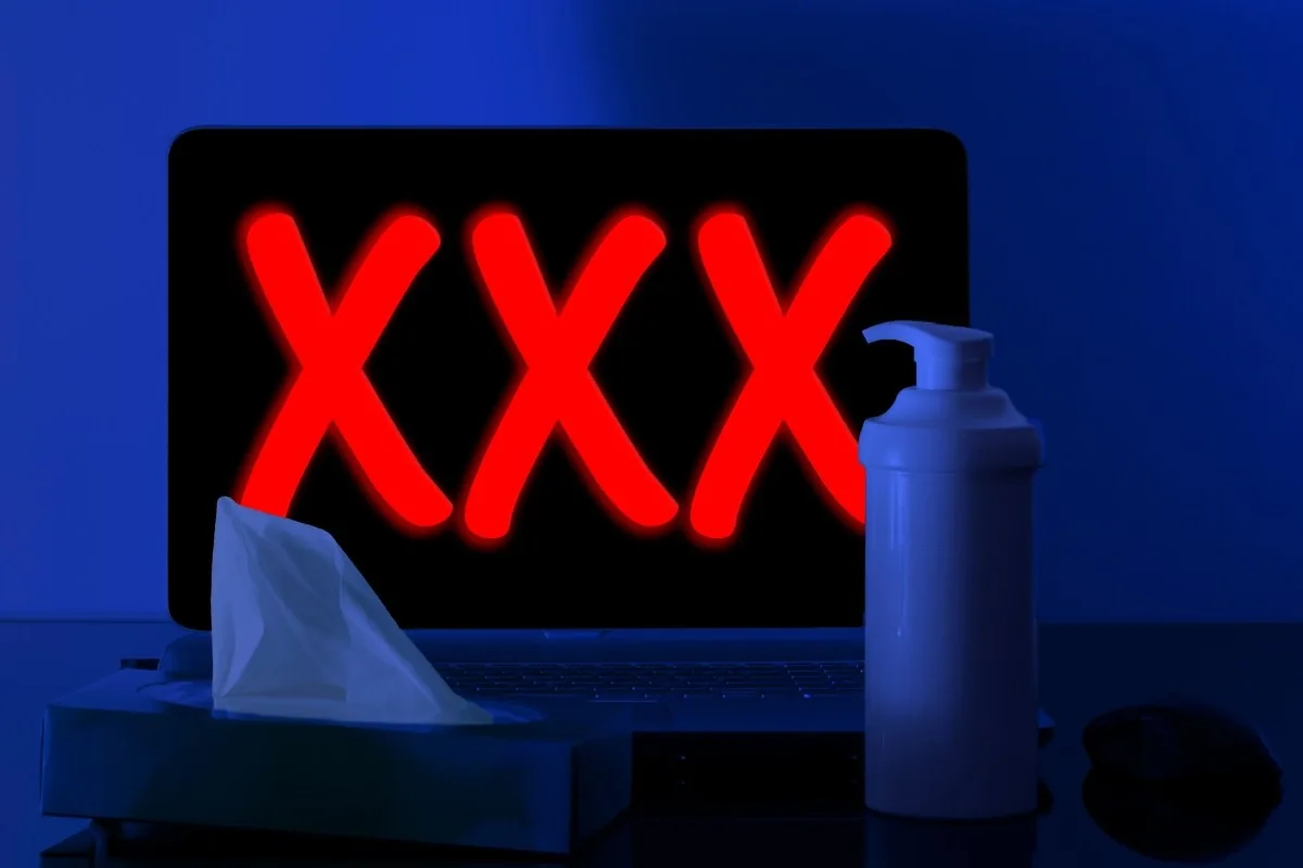 A laptop showing glowing red XXX letters beside a tissue box