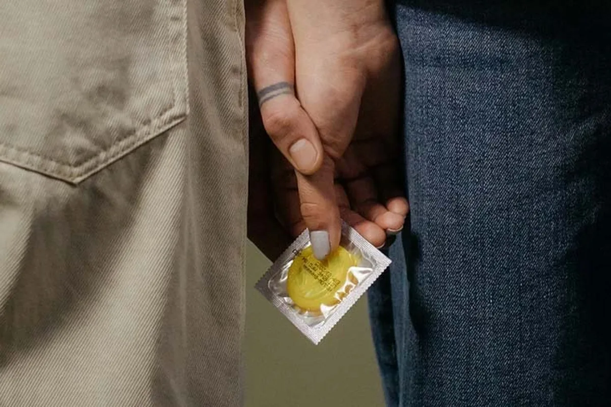One person passing a wrapped condom to another