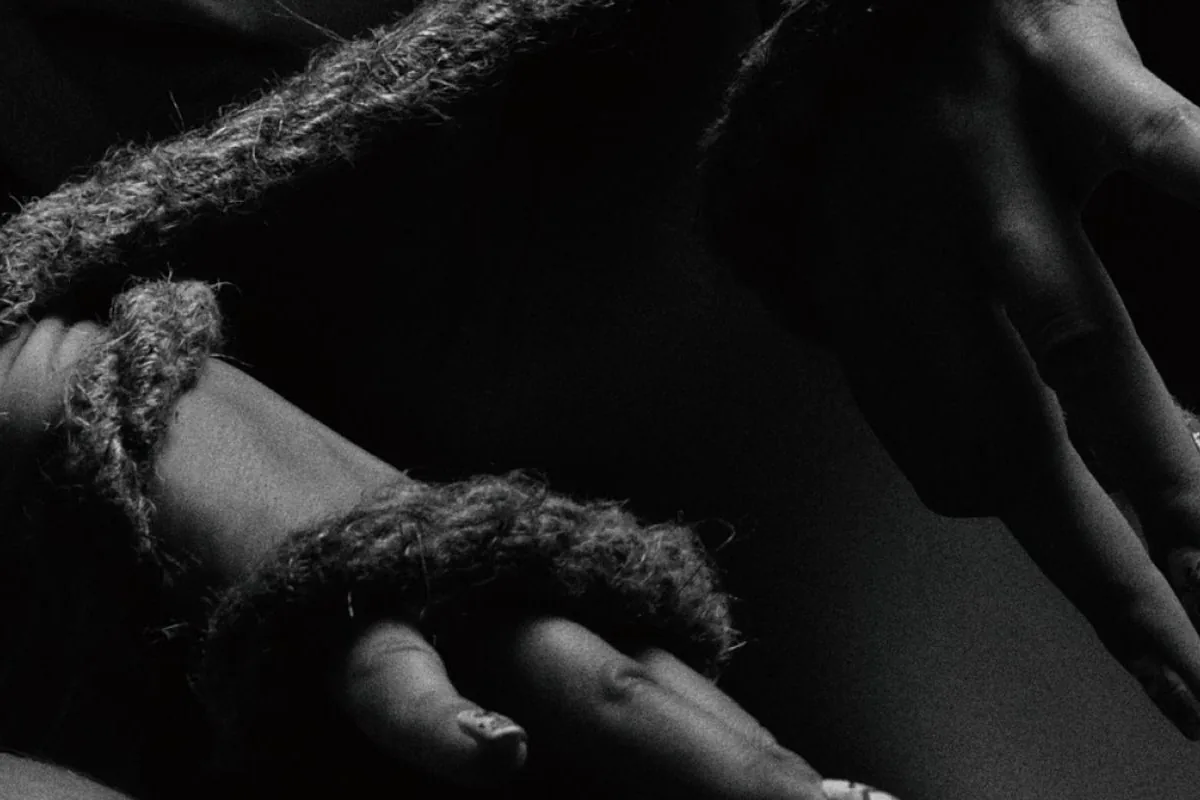 Black-and-white close-up of hands loosely wrapped in soft rope