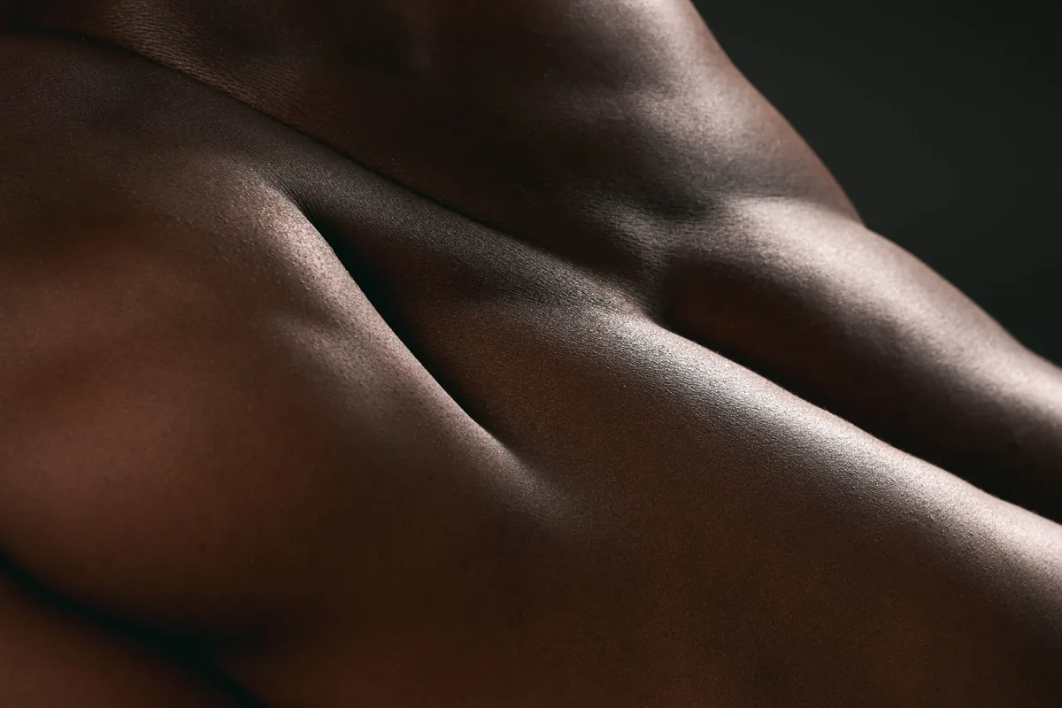 A fine-art close-up of an anonymous bare back and shoulder in dramatic light