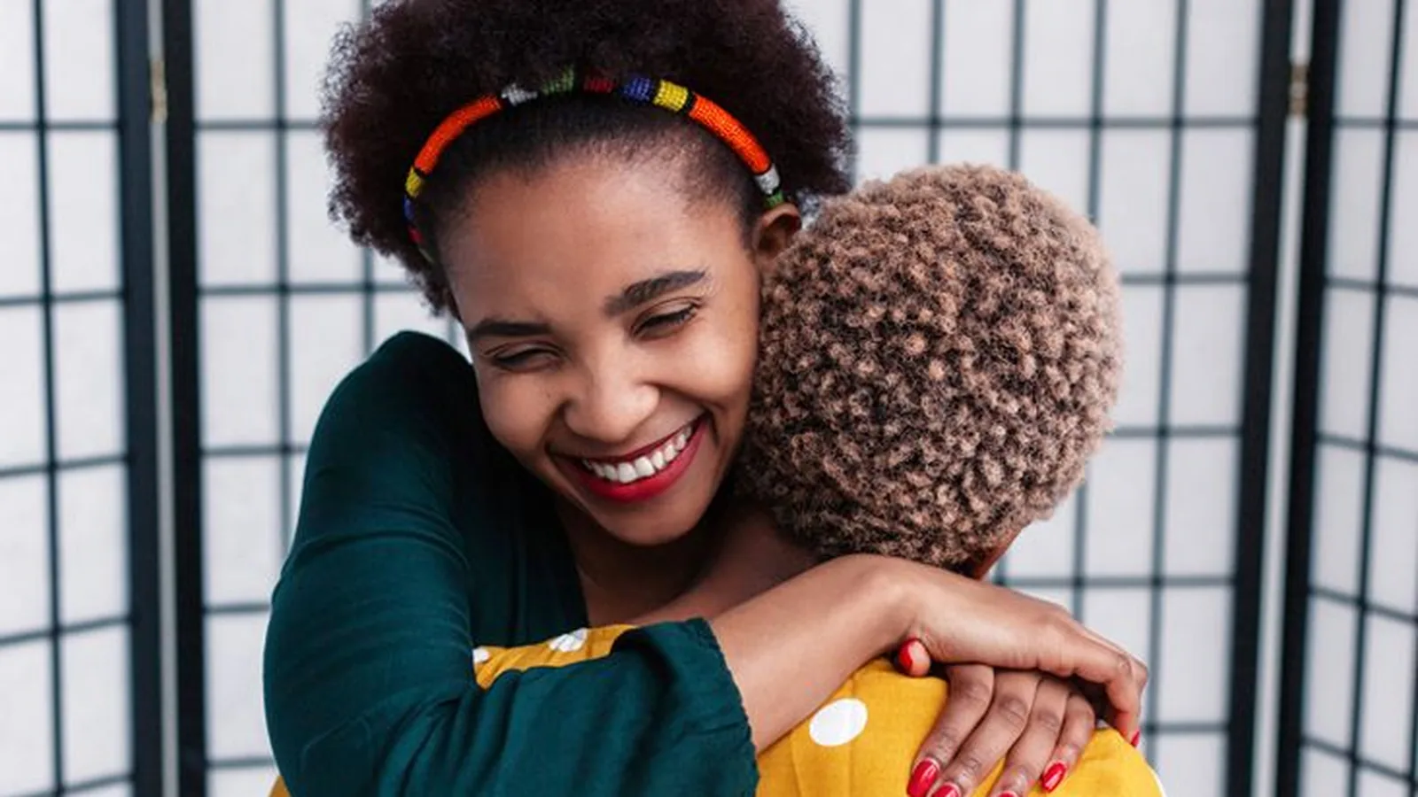 Two friends in a joyful hug, one smiling over the other's shoulder