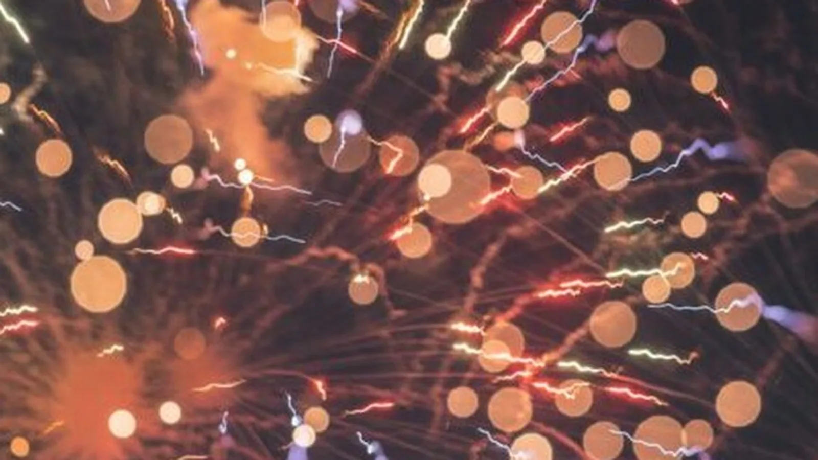 Bursts of fireworks and glowing bokeh against a dark sky