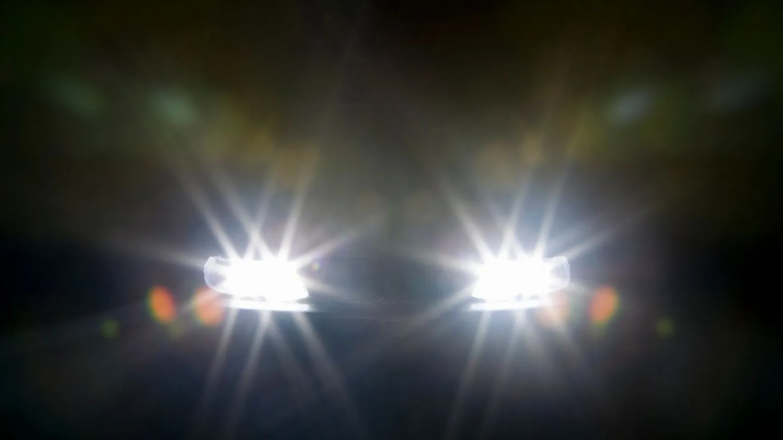 Two car headlights glowing in the dark